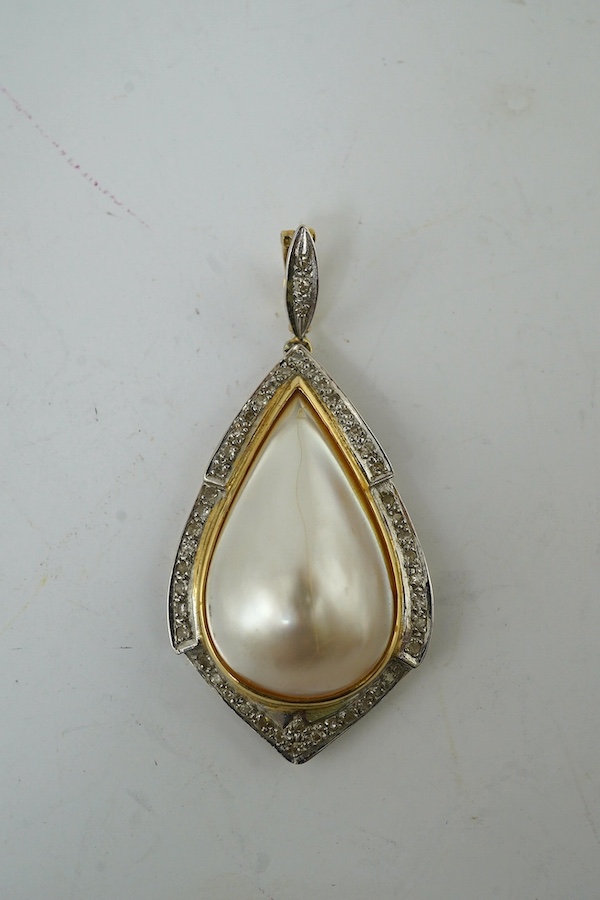 A modern yellow metal, mother of pearl and diamond chip set pear shaped pendant, overall 43mm, together with an Indian? yellow metal pendant, inset with figure. Condition - fair